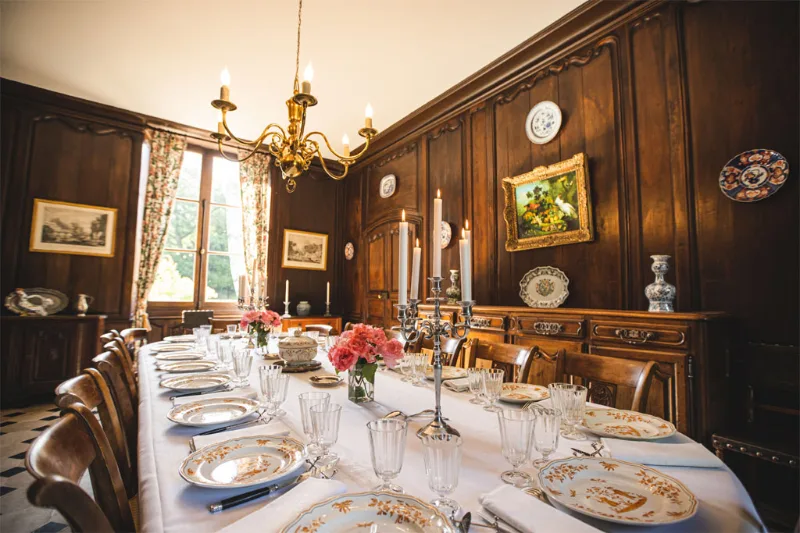 Salle à manger du château avec grande table pour 25 personnes, parquet et lustre ancien