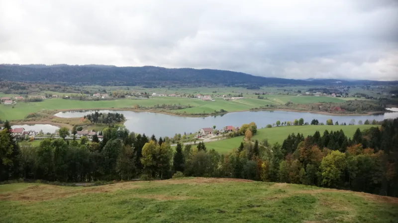 Vue plongeante sur le lac et les collines verdoyantes du Haut-Jura depuis les hauteurs du domaine
