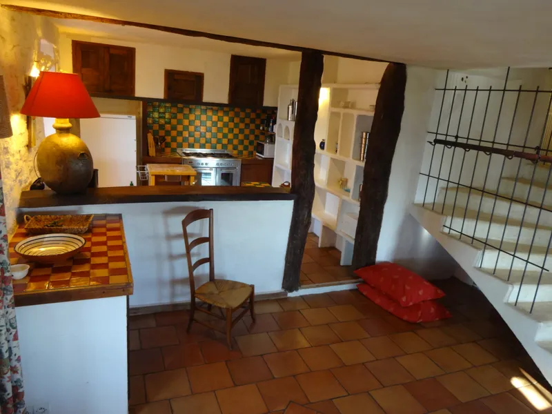 Cuisine équipée avec crédence en carreaux vernissés verts et jaunes, cuisinière et réfrigérateur