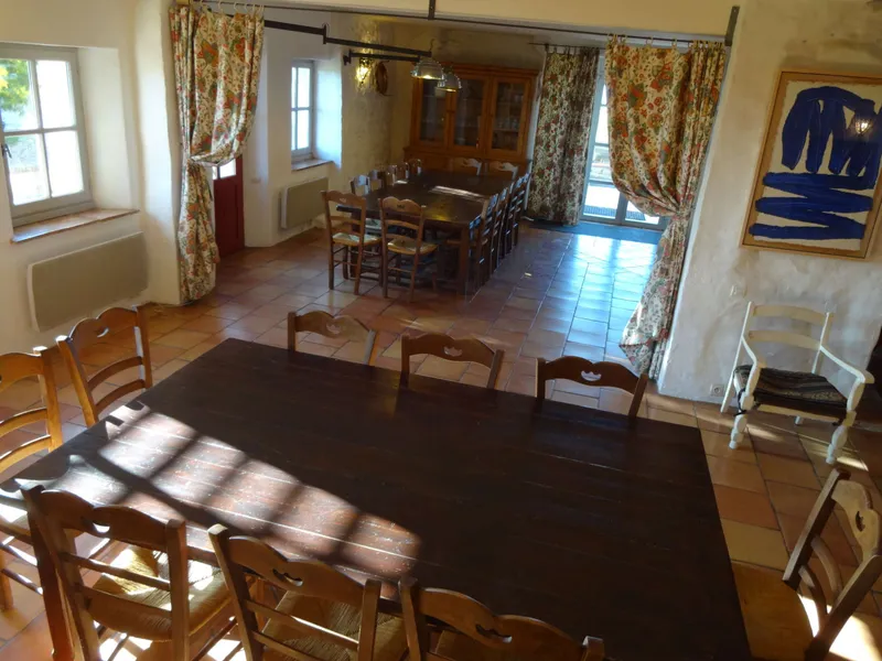 Grande salle à manger commune avec longue table en bois sombre et chaises paillées en enfilade