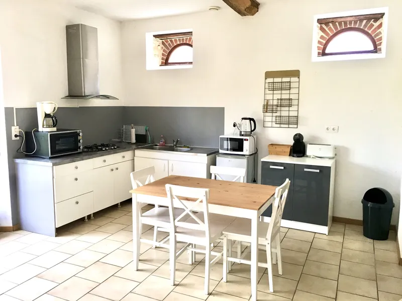 Cuisine équipée avec plaques gaz, hotte inox, four micro-ondes et grande table à manger