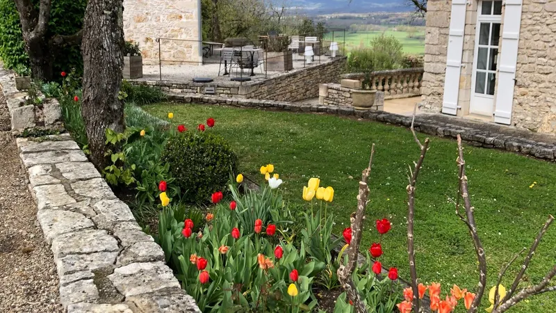 Vue aérienne du domaine avec bâtiments en pierre à toits de tuiles et de lauzes, allées et grand parc arboré