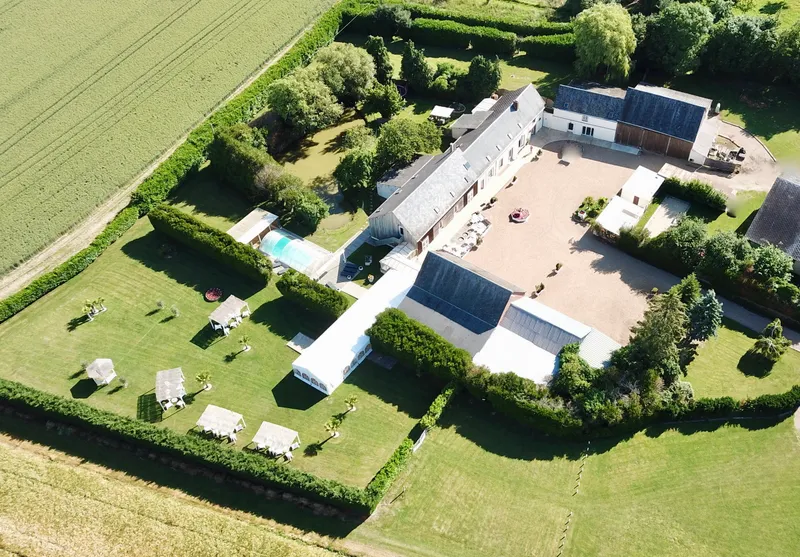 Vue aérienne du domaine avec bâtisses en pierre et toits d'ardoise, piscine couverte et grand parc arboré clos de haies