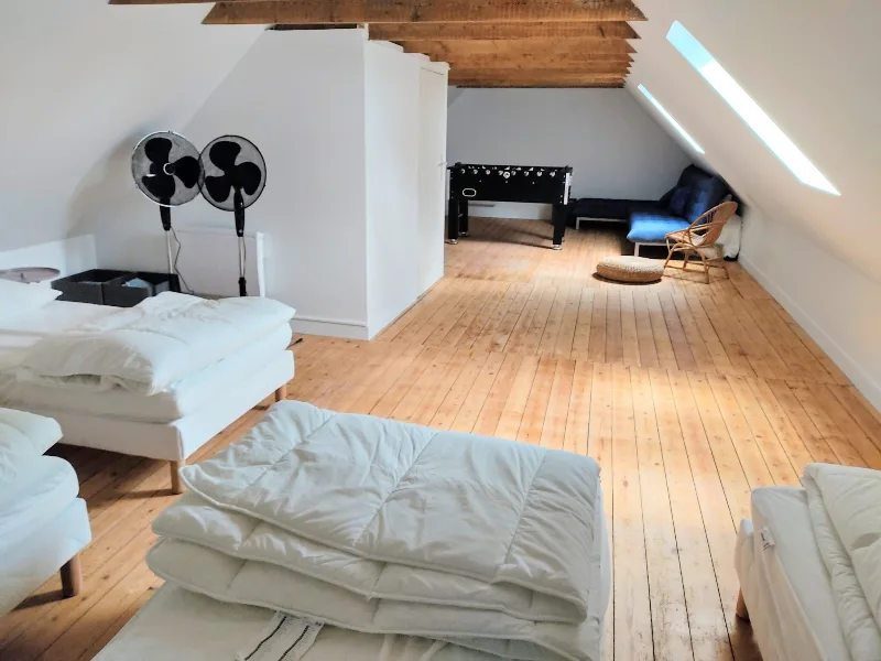 Espace détente sous les combles avec babyfoot, matelas et poutres apparentes