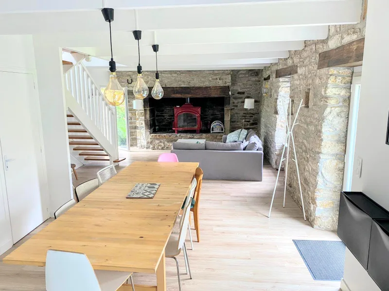 Grande pièce de vie ouverte avec table à manger en bois, suspensions design et escalier blanc
