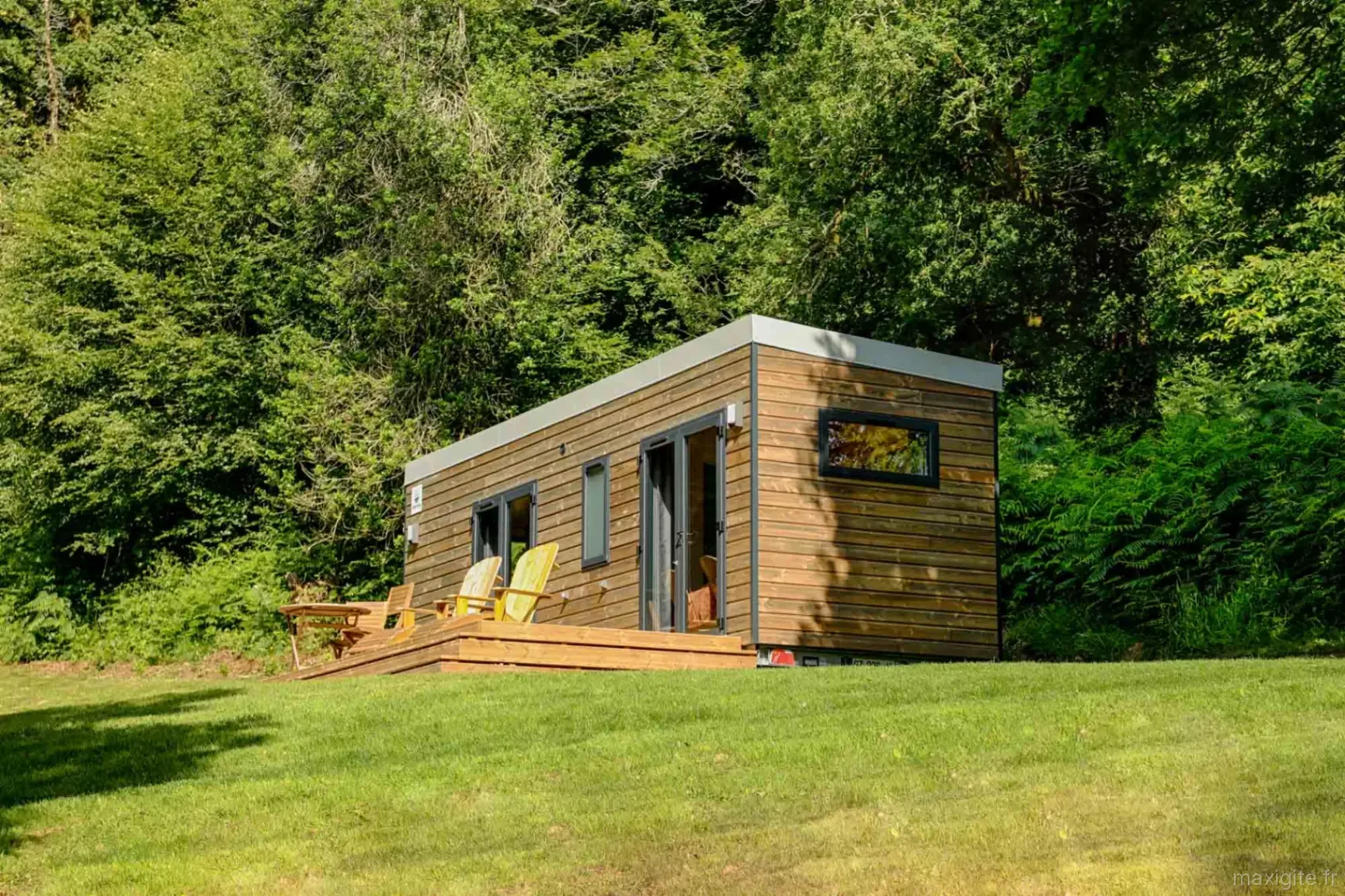 Tiny house Tilleul en bardage bois avec terrasse, posée dans une clairière verdoyante