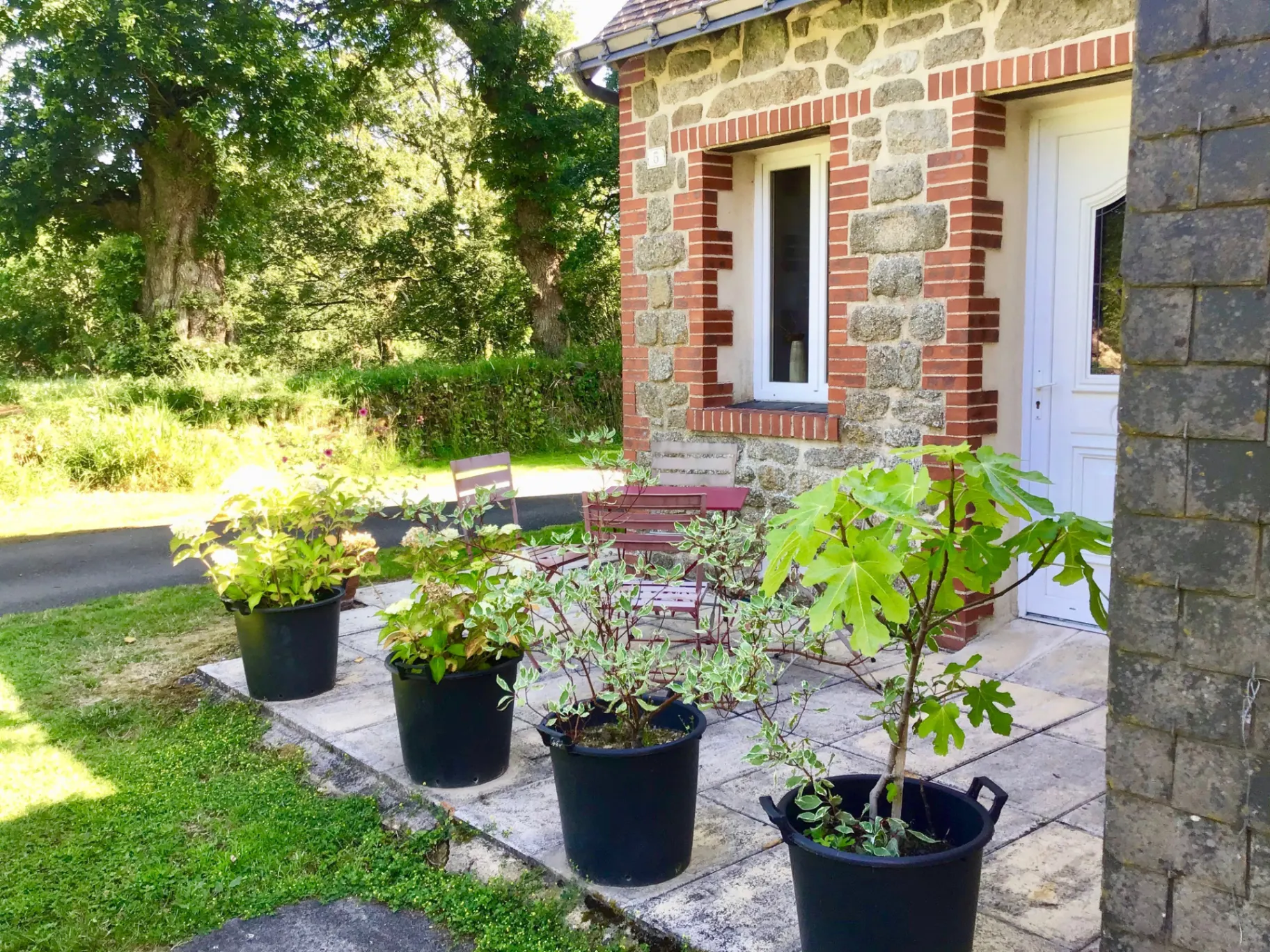 Petite maison en brique et granit avec terrasse et pots de fleurs colorés