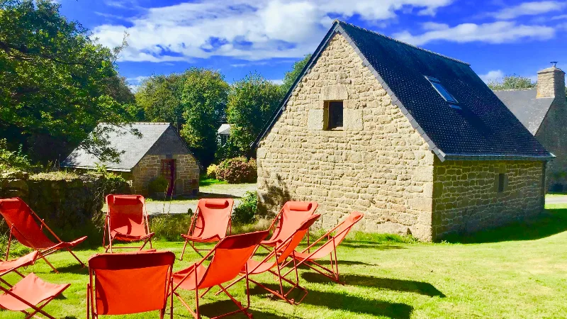Chaises longues rouges sur la pelouse face à un bâtiment en granit du XVIIIe siècle