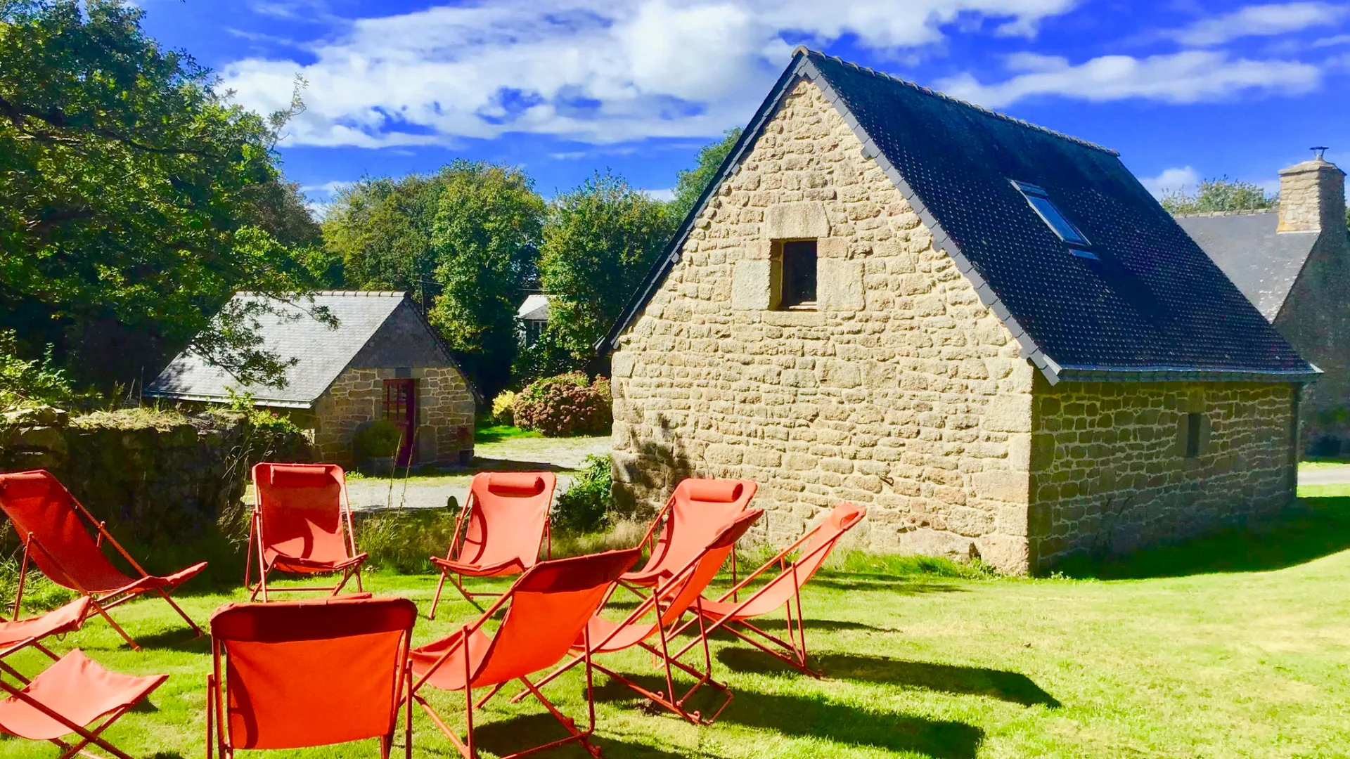 Chaises longues rouges sur la pelouse face à un bâtiment en granit du XVIIIe siècle