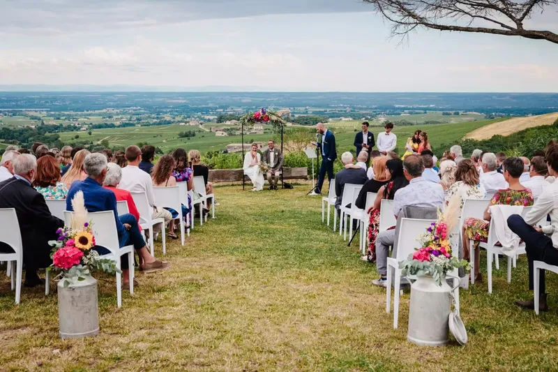 Cérémonie de mariage en plein air avec invités assis face à la vue panoramique sur la plaine du Beaujolais