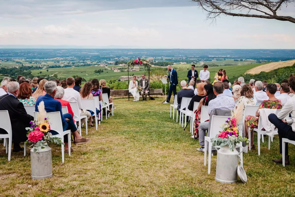 Cérémonie de mariage en plein air avec invités assis face à la vue panoramique sur la plaine du Beaujolais
