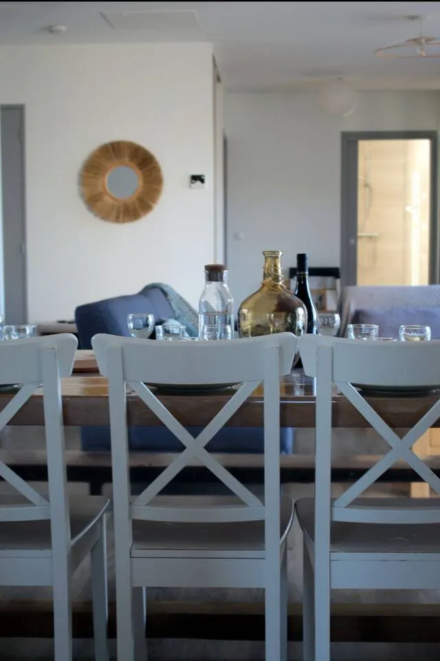 Coin repas du gite avec grande table en bois massif, chaises blanches et luminaire decoratif