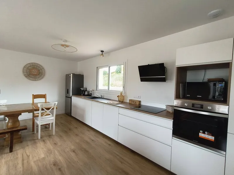 Cuisine equipee moderne avec four, micro-ondes, refrigerateur et plan de travail ouverte sur le salon