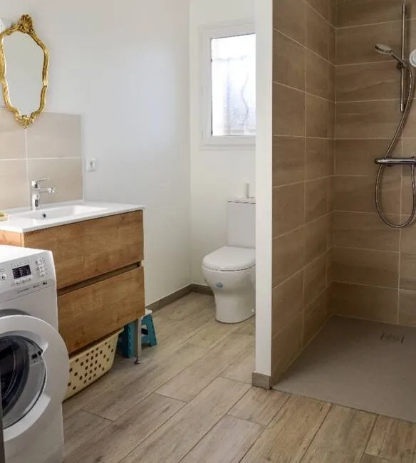 Seconde salle d'eau avec lave-linge, cabine de douche, WC et miroir dore