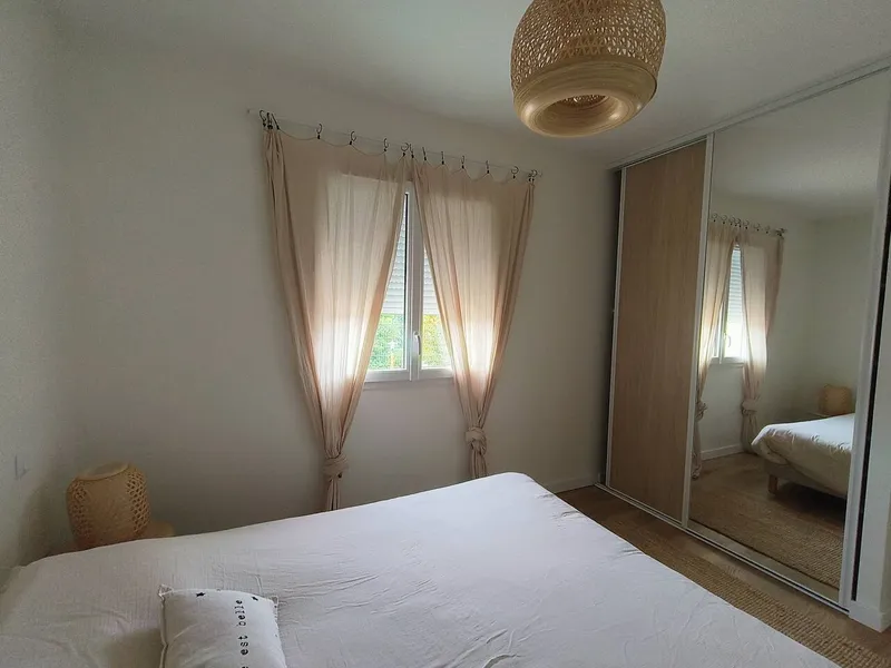 Chambre double avec lit deux places, armoire a miroir et decoration aux tons beiges