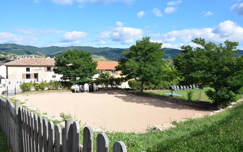 Cour extérieure du gîte La Girardière avec espace de jeux et terrain de pétanque