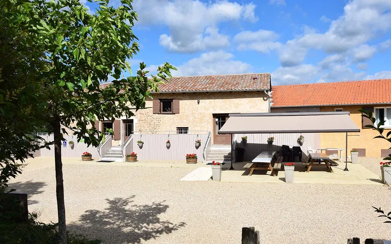 Espaces extérieurs privatifs du gîte avec tables ombragées et terrasse pour les groupes