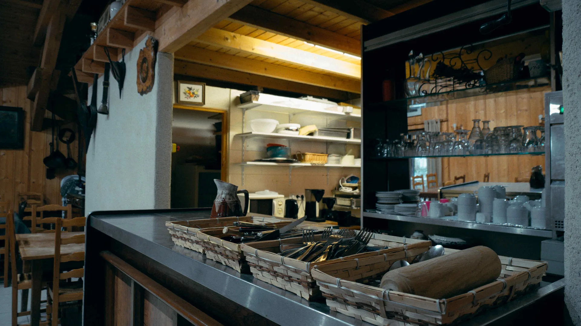 Coin cuisine avec comptoir bar et paniers en osier remplis de couverts, vaisselle rangée en arrière-plan