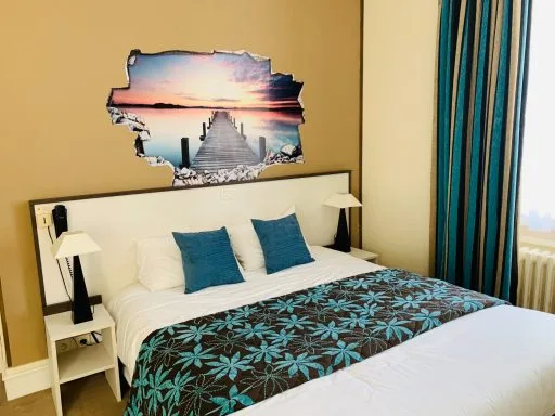 Chambre avec sticker mural en trompe-l'œil figurant un ponton au coucher du soleil, coussins bleu canard