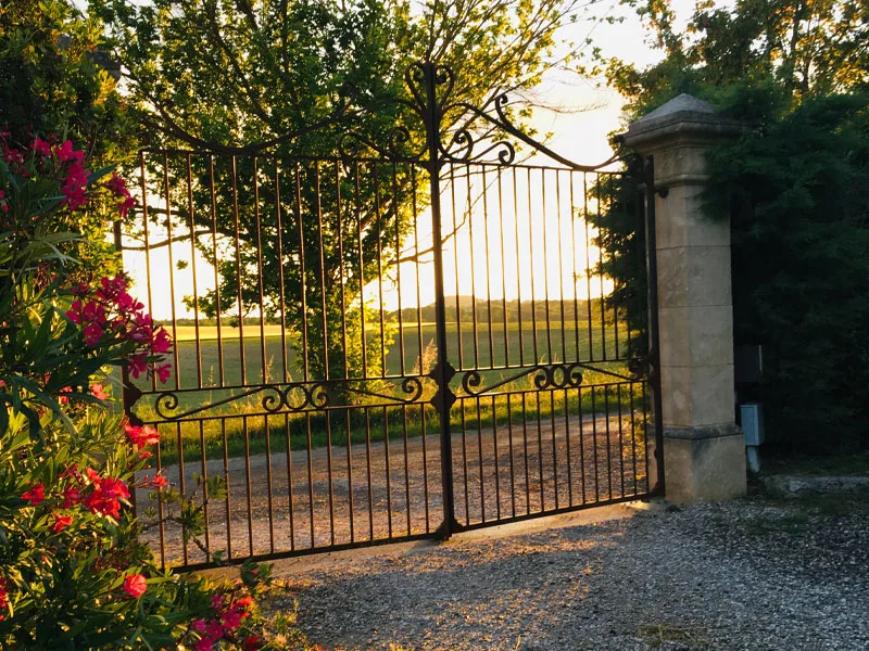Gîte de groupe Le Domaine d'Engrazac à Labastide-d'Anjou — Entrée du Domaine d'Engrazac avec allée bordée de verdure et façade en pierre, capacité 36 personnes