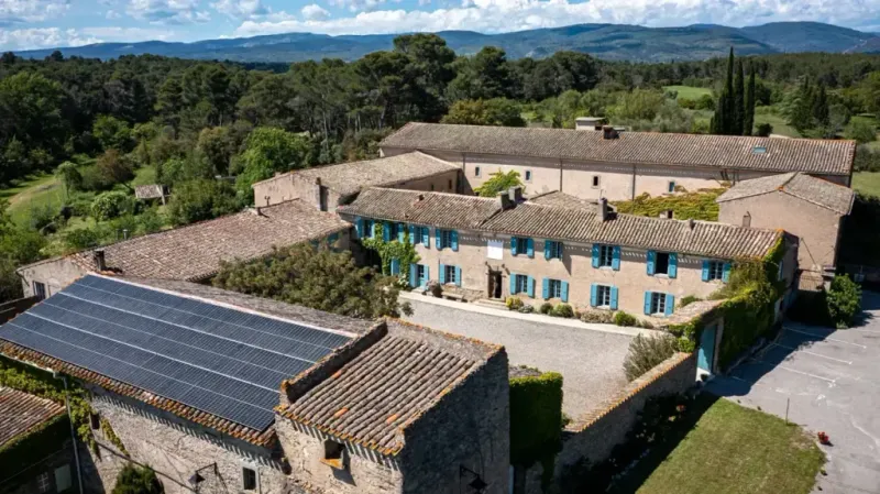 Vue d'ensemble aérienne du domaine avec les bâtiments en pierre et le parc boisé