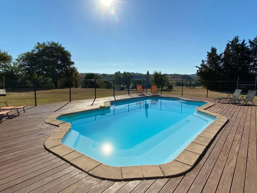 Gîte de groupe Maison Lafage à Lafage — Façade extérieure en pierre de Maison Lafage avec volets bleus et terrasse fleurie, capacité 14 personnes