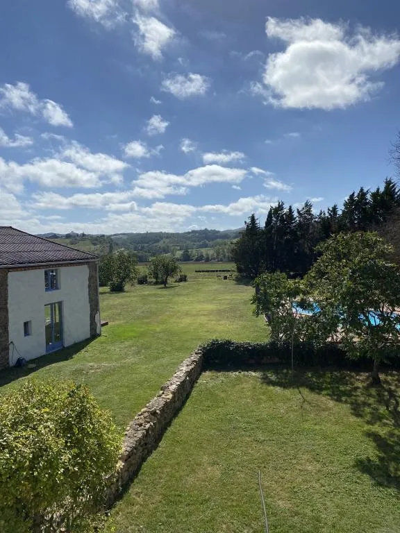 Vue extérieure du jardin avec arbres fruitiers et campagne vallonnée en arrière-plan