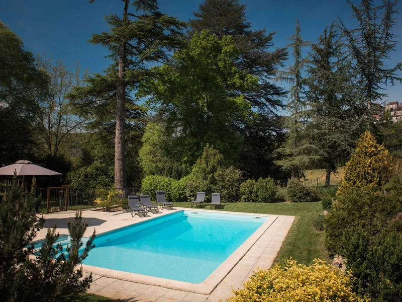 Piscine chauffée du Gîte La Rivière entourée de verdure et de transats