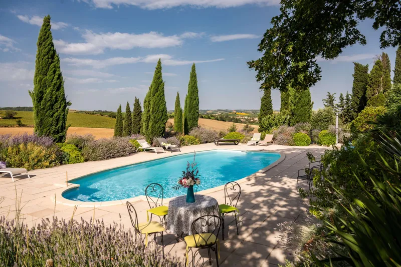 Piscine chauffee entouree de cypres, lavande et transats avec vue sur la campagne audoise